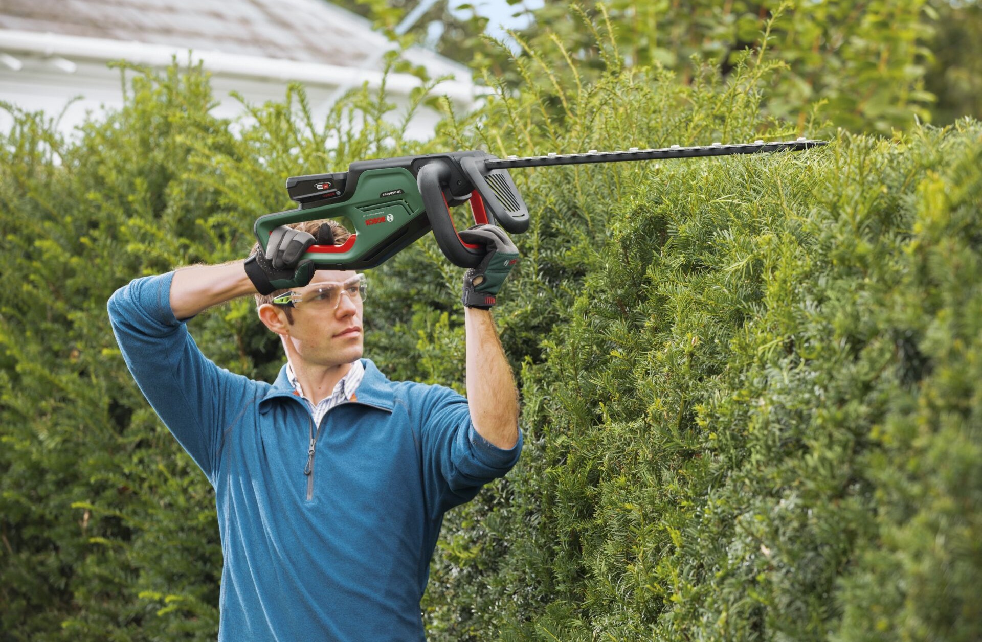 Mann nutzt Heckenschere zur Gartenpflege.