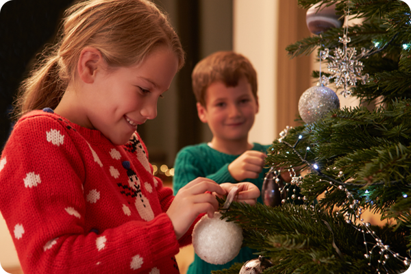 Zwei Kinder schmücken den Weihnachtsbaum